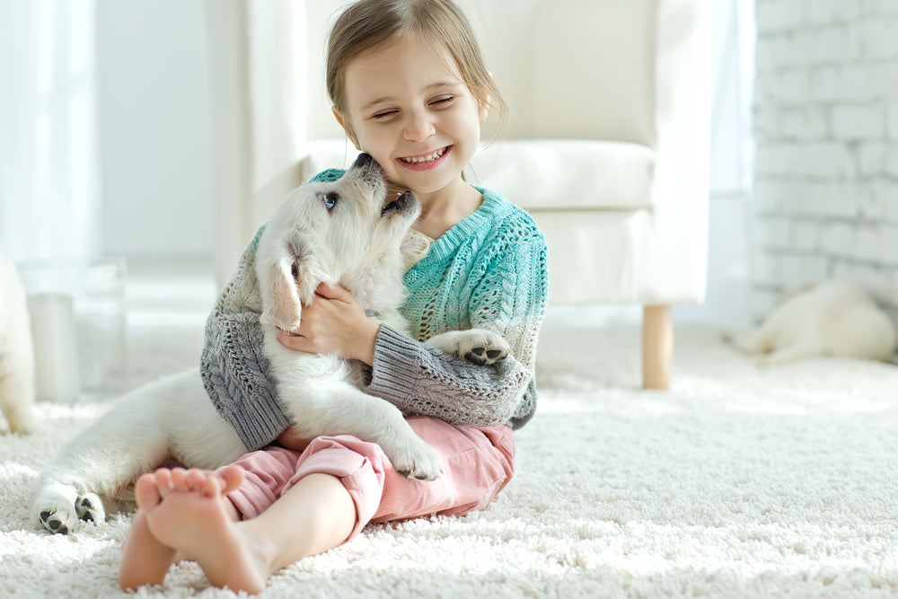 little girl hugging her puppy